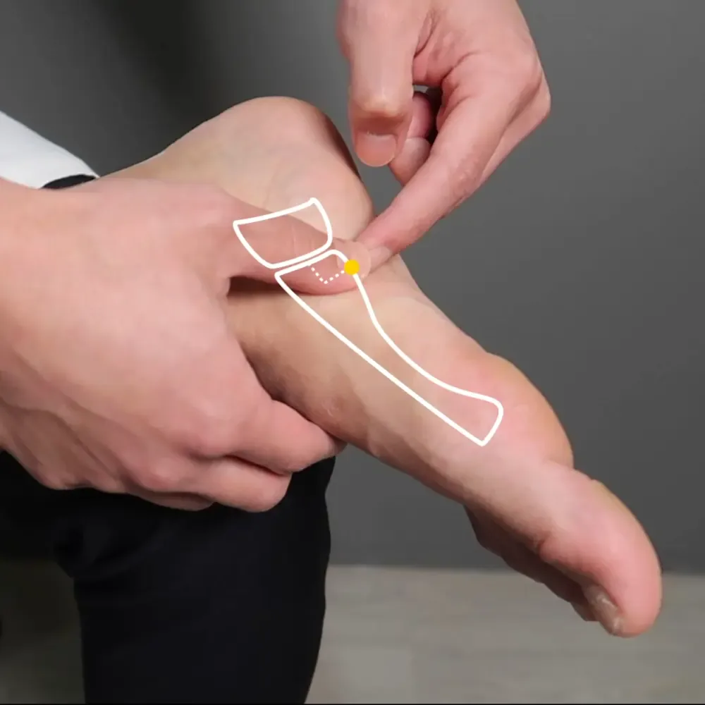 Finger locating Gong Sun SP4 on the medial foot below the first metatarsal base
