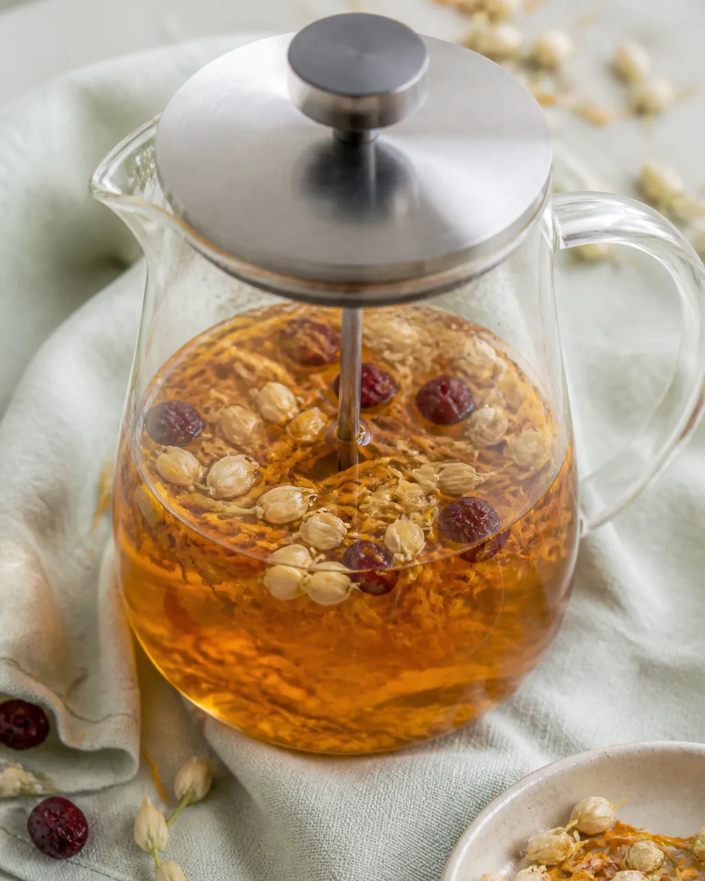 Jasmine, calendula, and cranberries steeping in a glass teapot for skin-brightening tea