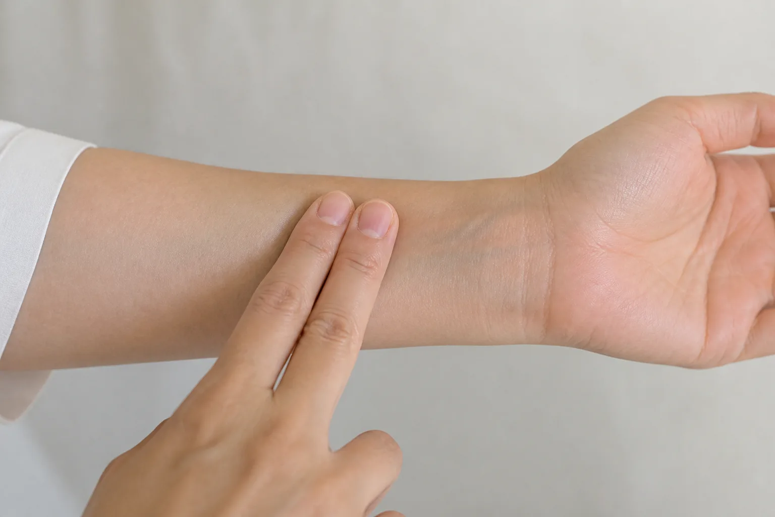 Fingers pressing Nei Guan PC6 on the inner forearm