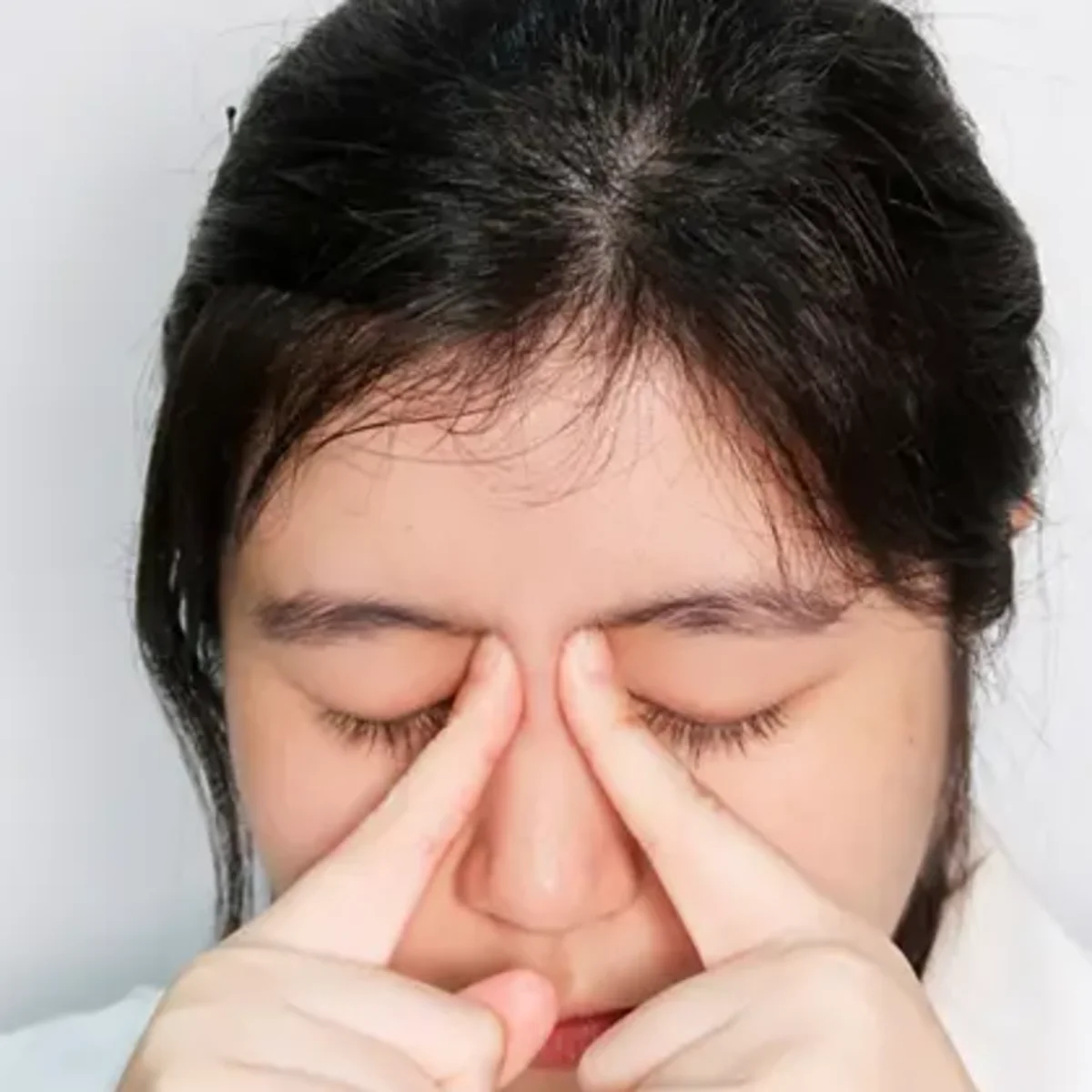 Fingers locating Jing Ming BL1 at the inner canthus for fatigue acupressure