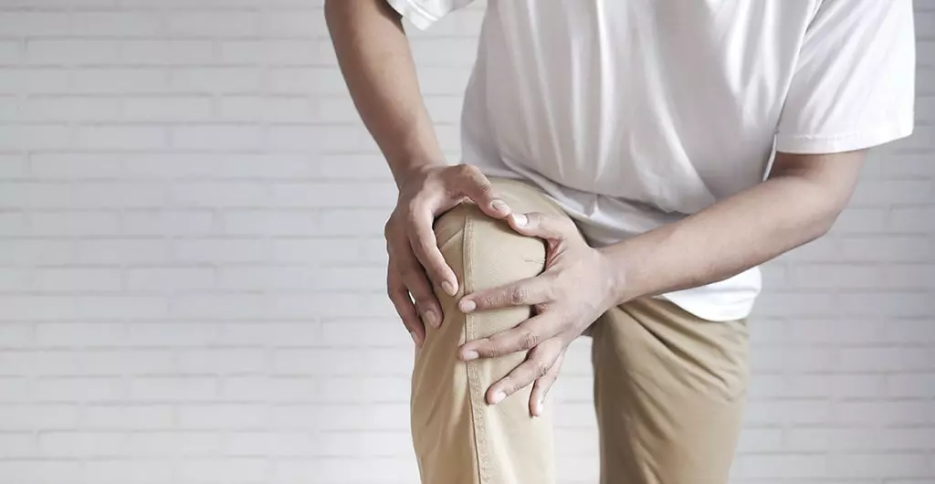 Hands holding a painful knee from rheumatoid arthritis