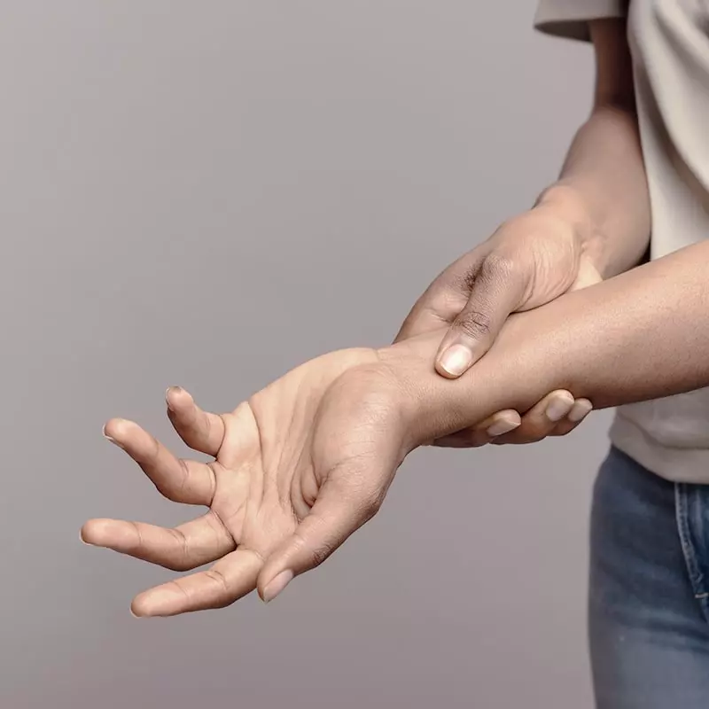 Hands supporting a painful wrist in rheumatoid arthritis