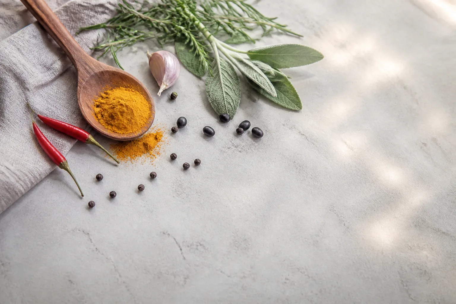 Fresh kitchen herbs, chilli, and spice on a pale board for TCM food therapy