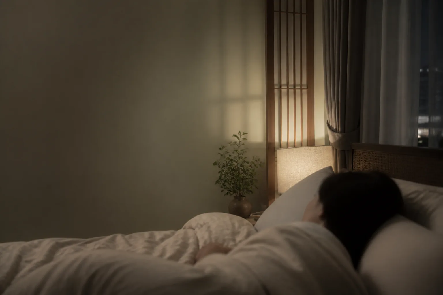 Quiet bedside lamp and rumpled bedding at night, illustrating stress-linked insomnia
