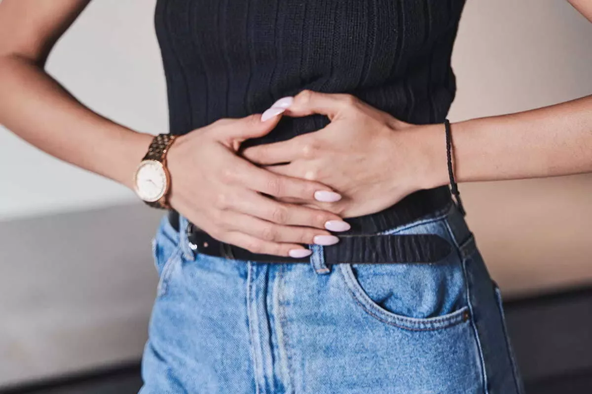 Hands on a bloated lower abdomen before menses