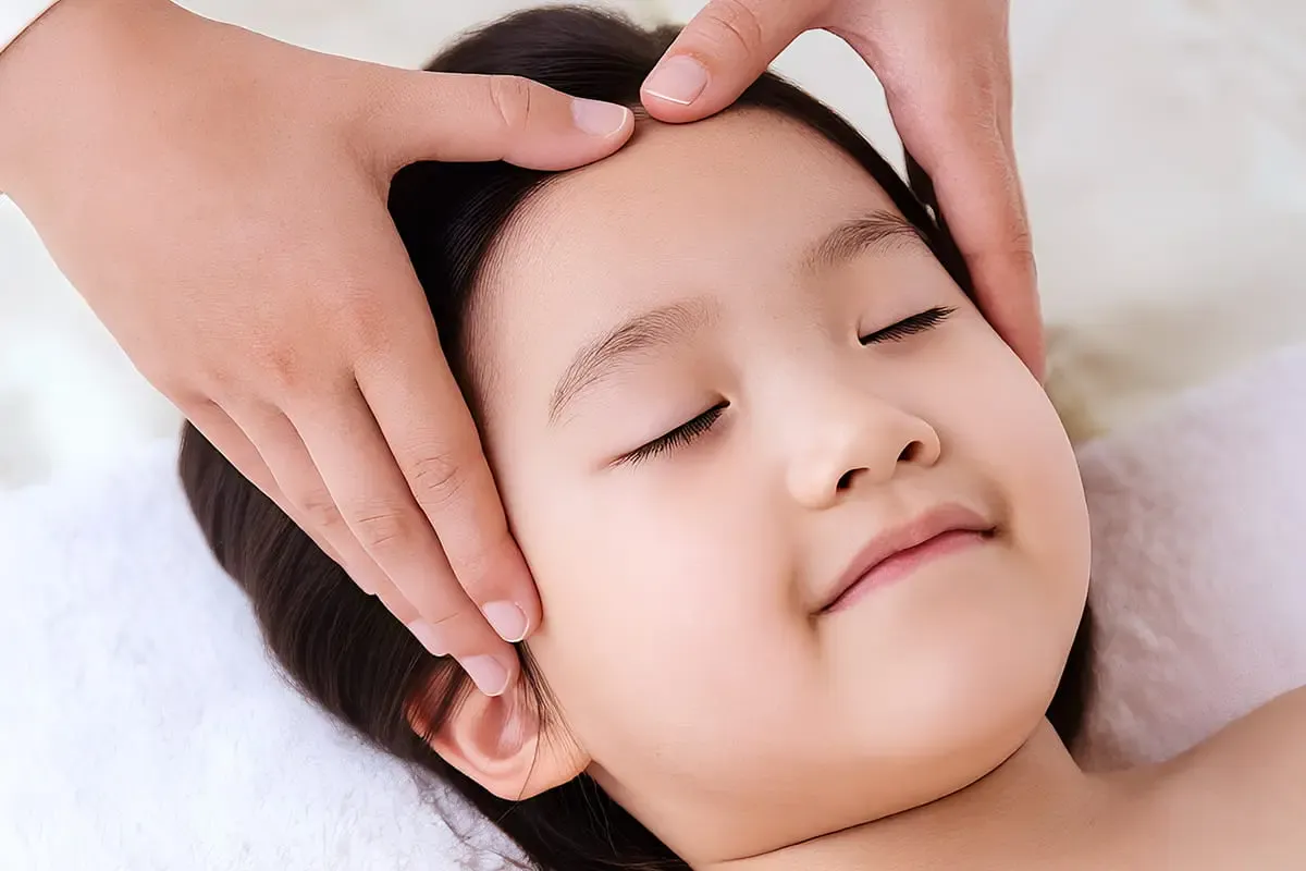 Gentle paediatric Tuina strokes across a child's scalp and face